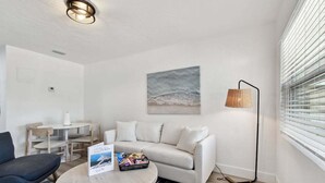 A modern living room with a round table, a sofa, a lamp, and a painting on the wall. - 1 Bedroom Treasure Island Getaway (Treasure Island)