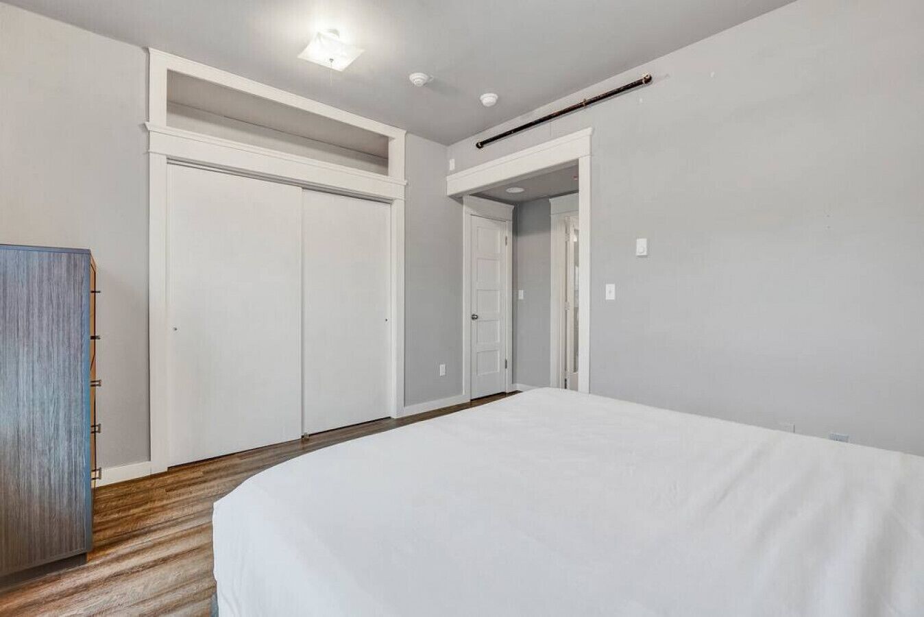 Une chambre d’hôtel avec un grand lit, une armoire et une porte donnant sur une autre pièce.
