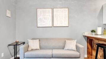 Un salon moderne avec un canapé gris, une table basse et des œuvres d’art abstraites accrochées au mur.