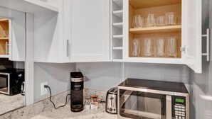 A kitchen with white cabinets, a microwave, a toaster, and a Keurig coffee maker. - Walk to DT Fast Wi-fi + Long Stay Equipped! (Tacoma)