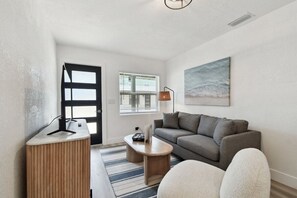 A modern living room with a sofa, a coffee table, a desk, and a lamp. - New Treasure Island Gem - Unit 3 (Treasure Island)