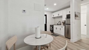 A modern kitchen with white cabinets, stainless steel appliances, and a round dining table with chairs. - New Treasure Island Gem - Unit 3 (Treasure Island)