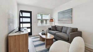A modern living room with a sofa, a coffee table, a side table, and a painting on the wall. - New Treasure Island Gem - Unit 3 (Treasure Island)