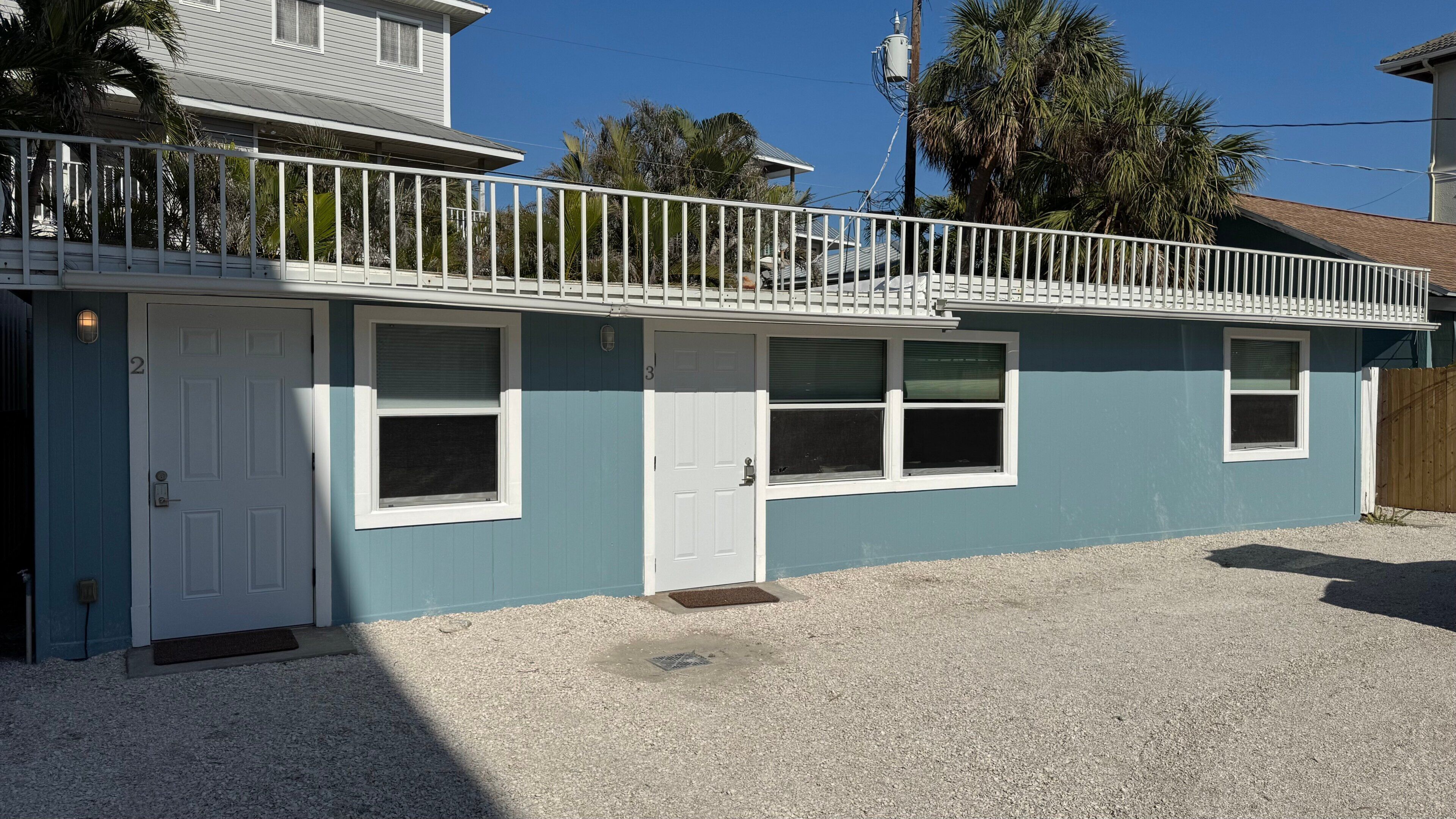 Una casa a due piani con un balcone, un garage e una strada privata.