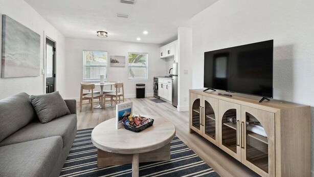A modern living room with a sofa, coffee table, TV, and wooden cabinet. - Treasure Island Retreat (Treasure Island)