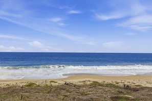 Une plage avec des vagues, un ciel dégagé et une végétation clairsemée.