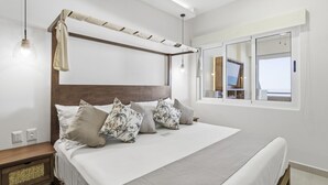 Camera da letto con un letto, cuscini, un comodino, una finestra e una lampada a sospensione.