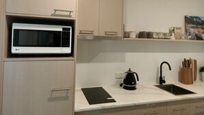 A modern kitchen with a built-in microwave, a coffee maker, and a sink. - Cosy 1 Bedroom Unit with separate living space, laundry and kitchen. (Prospect Vale)