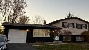 Ein zweistöckiges Haus mit Garage, Auffahrt und Rasen.