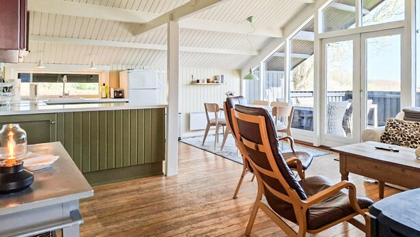 A spacious kitchen with a large island, wooden flooring, and a view of the outdoors through large windows. - 3 bedroom nice home in Haarby (Haarby)