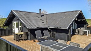 A cabin with a sloped roof, outdoor seating area, and a deck. - 3 bedroom nice home in Haarby (Haarby)