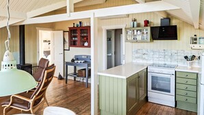 A kitchen with a stove, cabinets, and a dining area with chairs and a table. - 3 bedroom nice home in Haarby (Haarby)