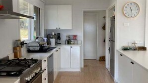 Een moderne keuken met witte kasten, een gasfornuis en een houten vloer.