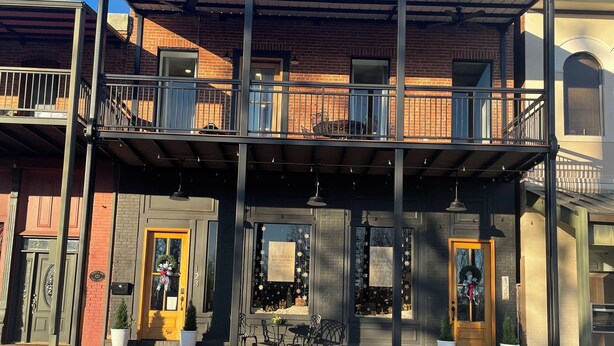 En toetagers bygning med balkon, butiksvindue og gadesyn.