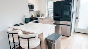 Una cocina moderna con una isla blanca, electrodomésticos de acero inoxidable y un cubo de basura.