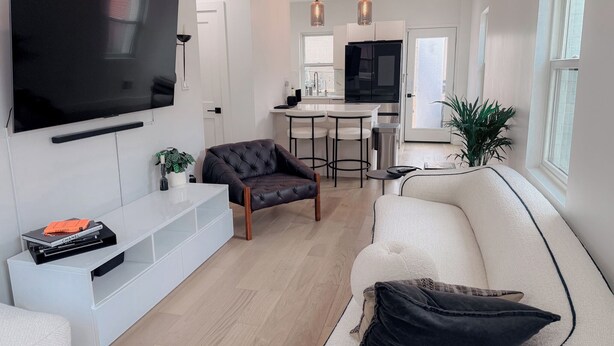 Una sala moderna con un televisor de pantalla plana, un sofá, una butaca y una mesita con libros.
