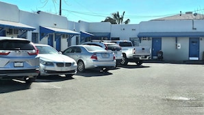 A row of parked cars in a parking lot with a building in the background.