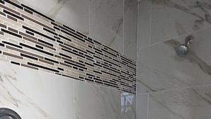 A modern bathroom with marble tiles, a shower, and a hexagonal patterned floor.
