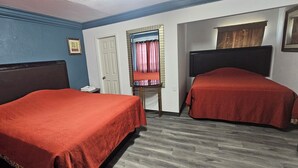 A room with two beds, a mirror, a door, and a small table with a telephone.
