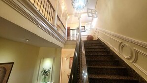 A grand staircase with a chandelier, a vase of flowers, and a framed picture on the wall. - Rural house in the heart of De la Vera in Yuste, Imperial retreat (Cuacos de Yuste)