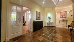 A spacious hallway with a checkered floor, a fireplace, and a staircase leading to an upper level. - Rural house in the heart of De la Vera in Yuste, Imperial retreat (Cuacos de Yuste)