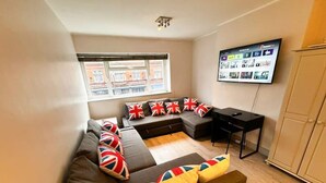Una sala de estar moderna con un sofá modular, un televisor de pantalla plana y un ventanal con vista a la ciudad.