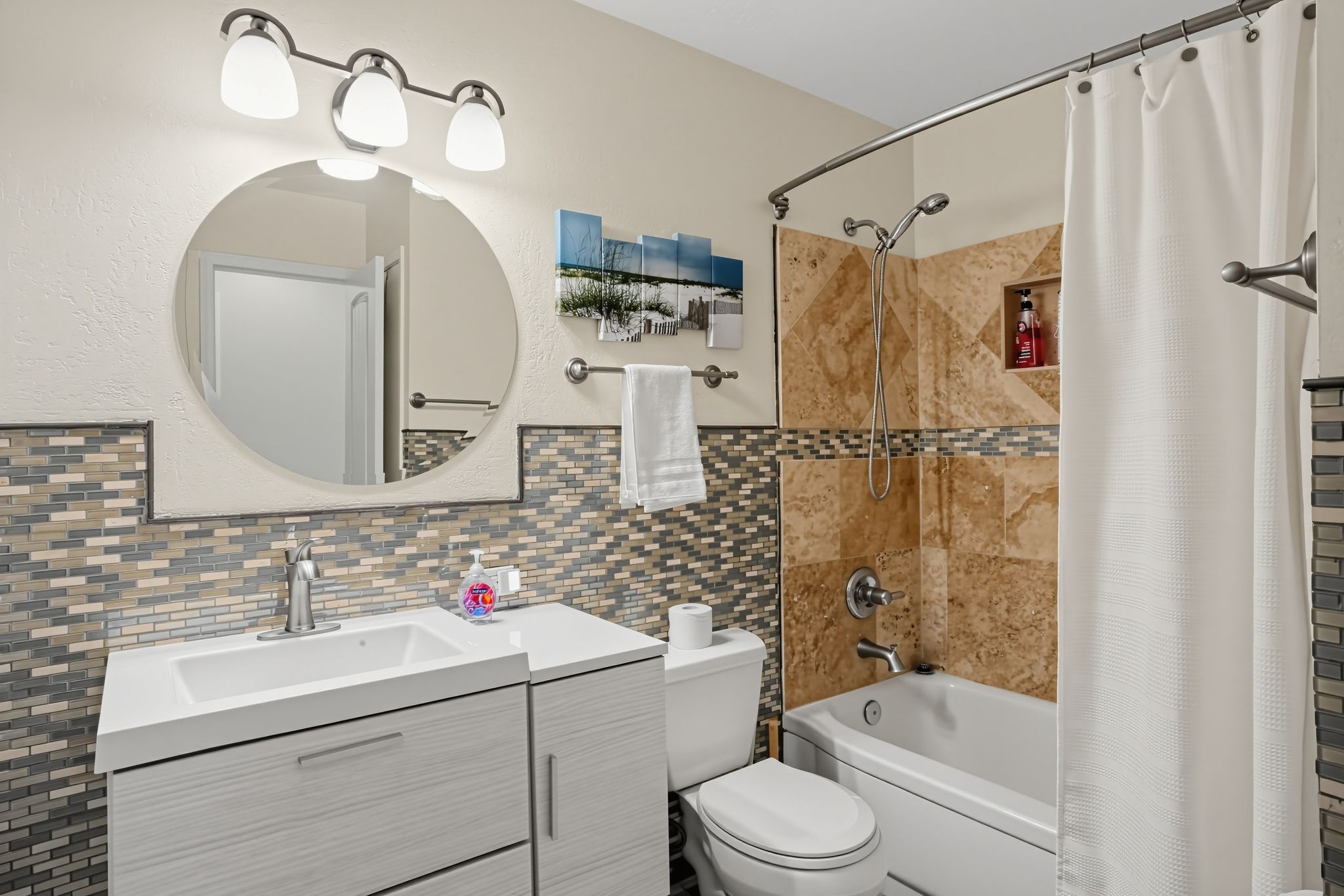 A bathroom with a double sink vanity, a toilet, a bathtub, and a shower curtain.