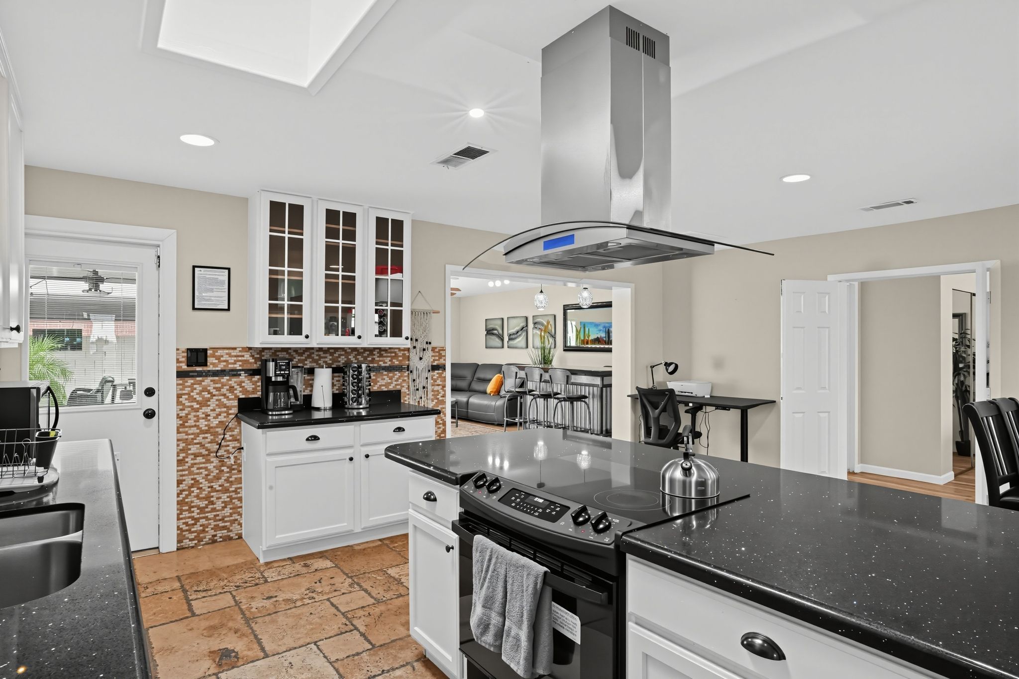 A modern kitchen with a central island, built-in cabinets, and a large stove.