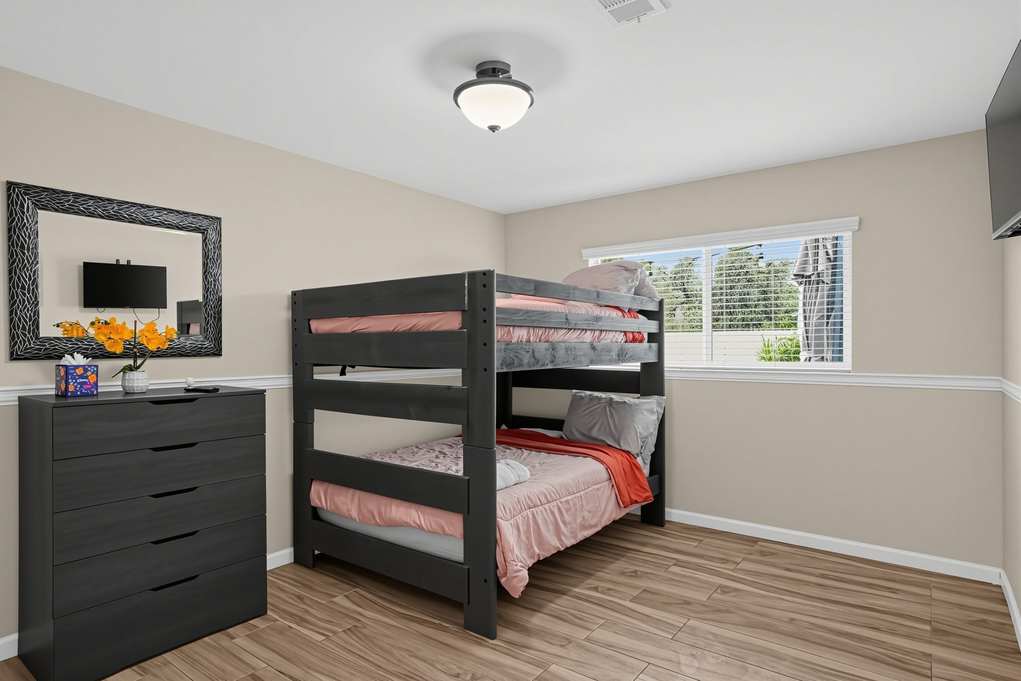 A bedroom with a bunk bed, a dresser, a mirror, and a window with blinds.