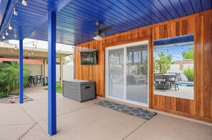 A covered patio area with a ceiling fan, a television mounted on the wall, and a view of a pool through a sliding glass door. - Scottsdale 3BR w/ Pool, Hot Tub & Putting Green (Scottsdale)