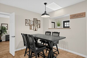 A dining area with a rectangular table, black chairs, a pendant light, and wall art. - Scottsdale 3BR w/ Pool, Hot Tub & Putting Green (Scottsdale)