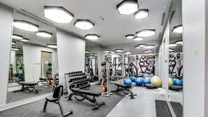 Uma academia com paredes espelhadas, equipamentos de musculação e bolas de exercício.