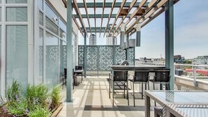 Um terraço no telhado com área de estar ao ar livre, pérgola e vista para a cidade.