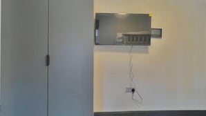 A room with a grey wardrobe, a wall-mounted shelf with a small device, and a power outlet. - Golder Greens London City Bliss Apartment (London)