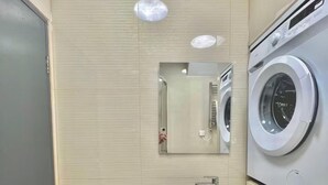 A compact bathroom with a washing machine, a sink, and a mirror. - Golder Greens London City Bliss Apartment (London)