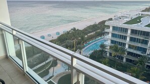 Un hôtel de grande hauteur doté d’une piscine, offrant une vue sur la plage et comprenant un espace paysager.