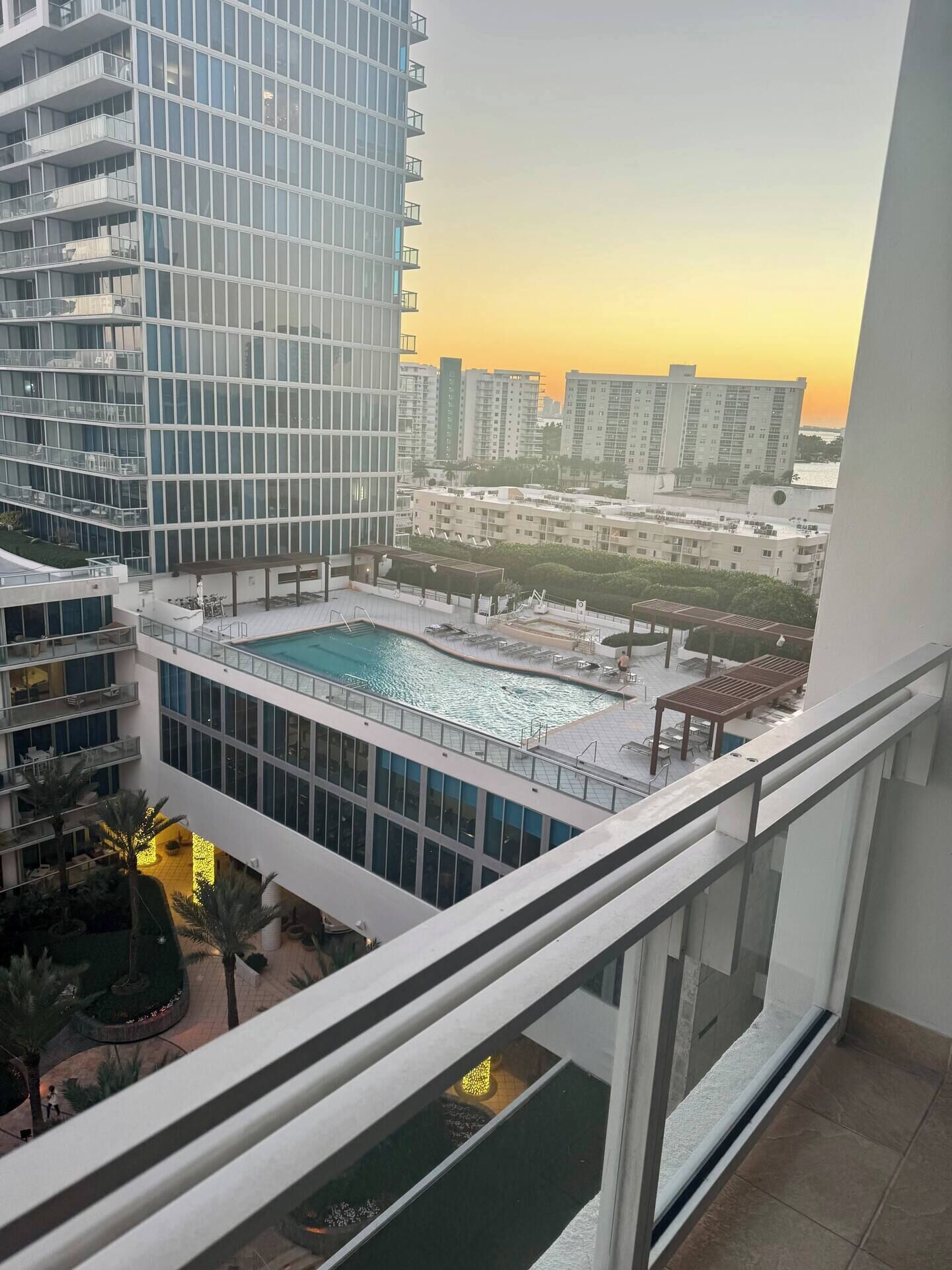 Un edificio de gran altura con piscina en la azotea y vista a otros edificios al fondo.
