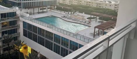 Un edificio de gran altura con piscina en la azotea y vista a otros edificios al fondo.