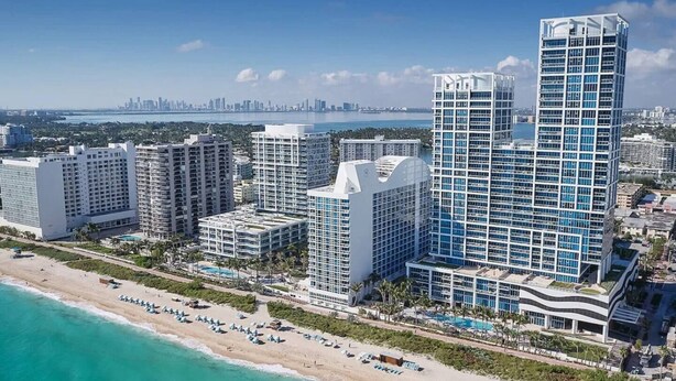 Un hôtel de grande hauteur, avec de nombreux étages, situé en bord de mer et offrant une vue sur le panorama urbain en arrière-plan.
