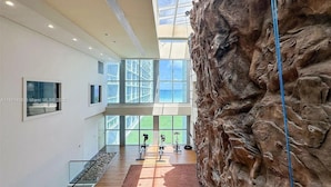 Un intérieur spacieux avec un plafond haut, de grandes fenêtres et un mur décoratif qui ressemble à de la roche.