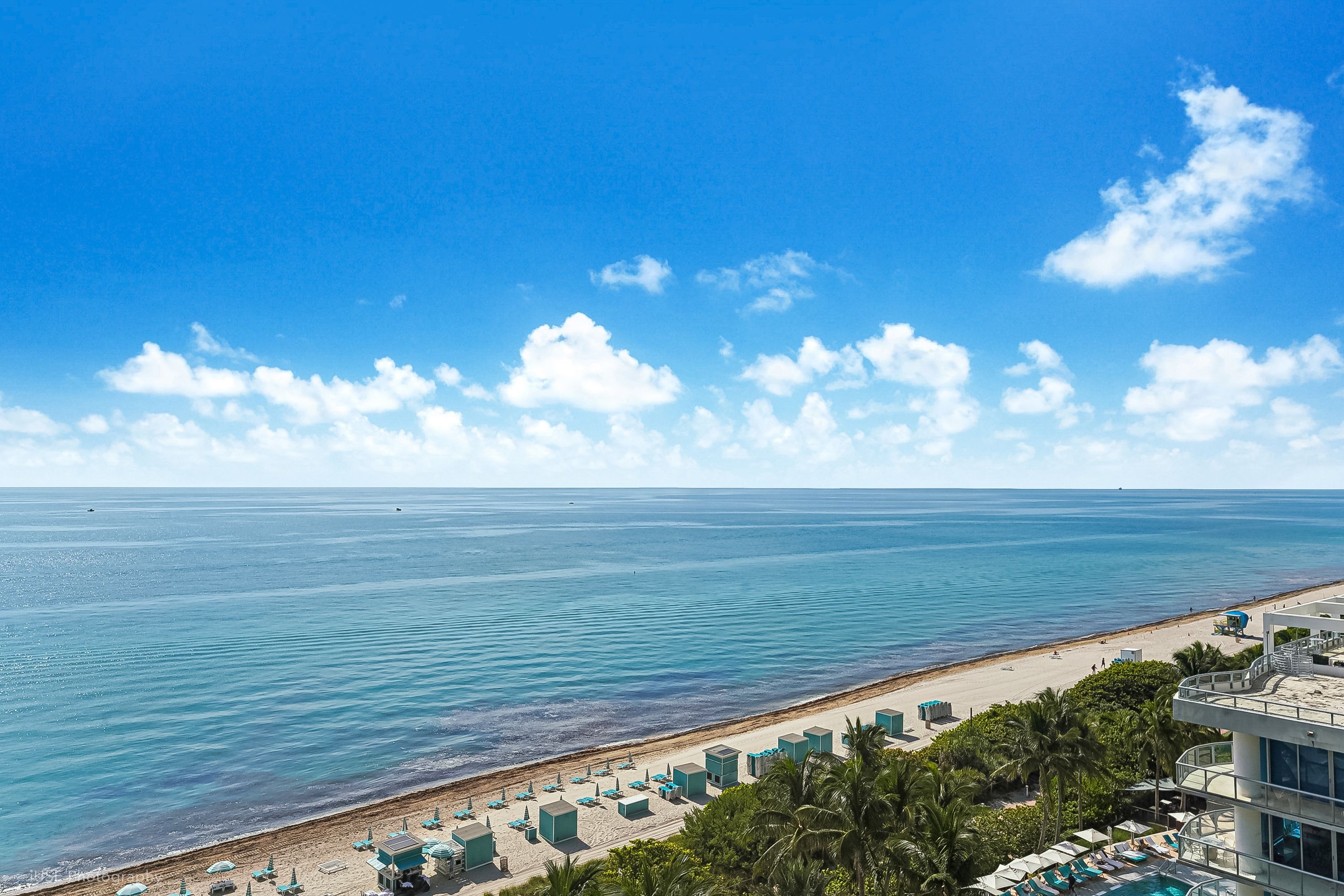 A beach resort with a view of the ocean, a sandy beach, and a pool area.