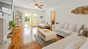 A spacious living room with hardwood flooring, a white sofa, a coffee table, and a ceiling fan. - 1223 Settlebench Ln NW Kennesaw (Kennesaw)