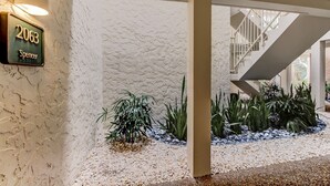 A modern building entrance with a textured wall, a sign reading "2063 Spencer," and a staircase leading to an upper level. - 2063 Beachwood Lovely 2 Bedroom, 2 Bath Beach Wood Villa is Located in Amelia Island Plantation Resort (Fernandina Beach)