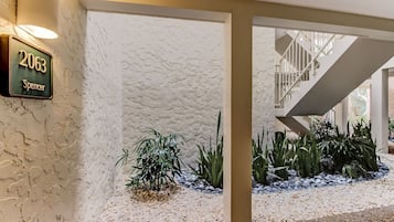 Une entrée moderne, avec un mur à texture, une enseigne indiquant « 2063 Spencer » et un escalier menant à un niveau supérieur.
