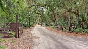 A forested area with a dirt path leading to a wooden gate. - 2063 Beachwood Lovely 2 Bedroom, 2 Bath Beach Wood Villa is Located in Amelia Island Plantation Resort (Fernandina Beach)