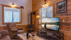 Ein gemütliches Blockhaus-Interieur mit Kamin, Fernseher und einer bequemen Sitzecke.