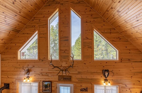 A cabin interior with wooden walls, triangular windows, and mounted animal skulls. - Henrys Post (Island Park)