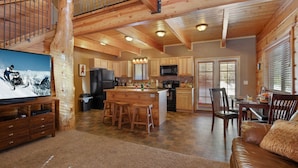 A spacious kitchen with wooden cabinets, a central island, and a dining area with chairs. - Rimfire Refuge (Island Park)