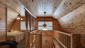 A wooden cabin with a loft bedroom, a staircase, and a ceiling fan. - Roger Dodger (Island Park)
