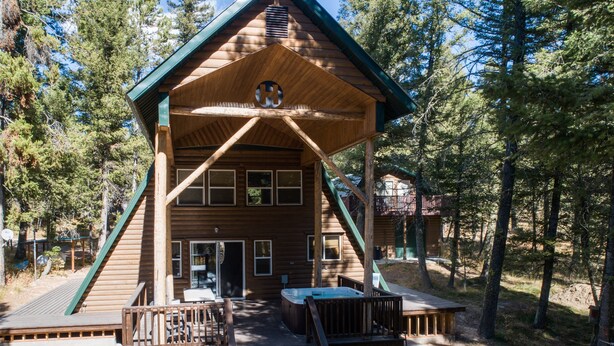 A wooden cabin with a porch, a hot tub, and a deck. - Roger Dodger (Island Park)
